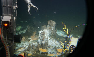 Greifarm eines Unterwasserroboters bei seiner Arbeit im Scheinwerferlicht